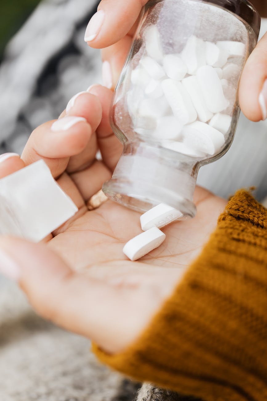 a close up shot of a person taking medicine from a bottle